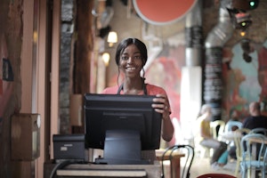 Black waitress in front of a restaurant cash register