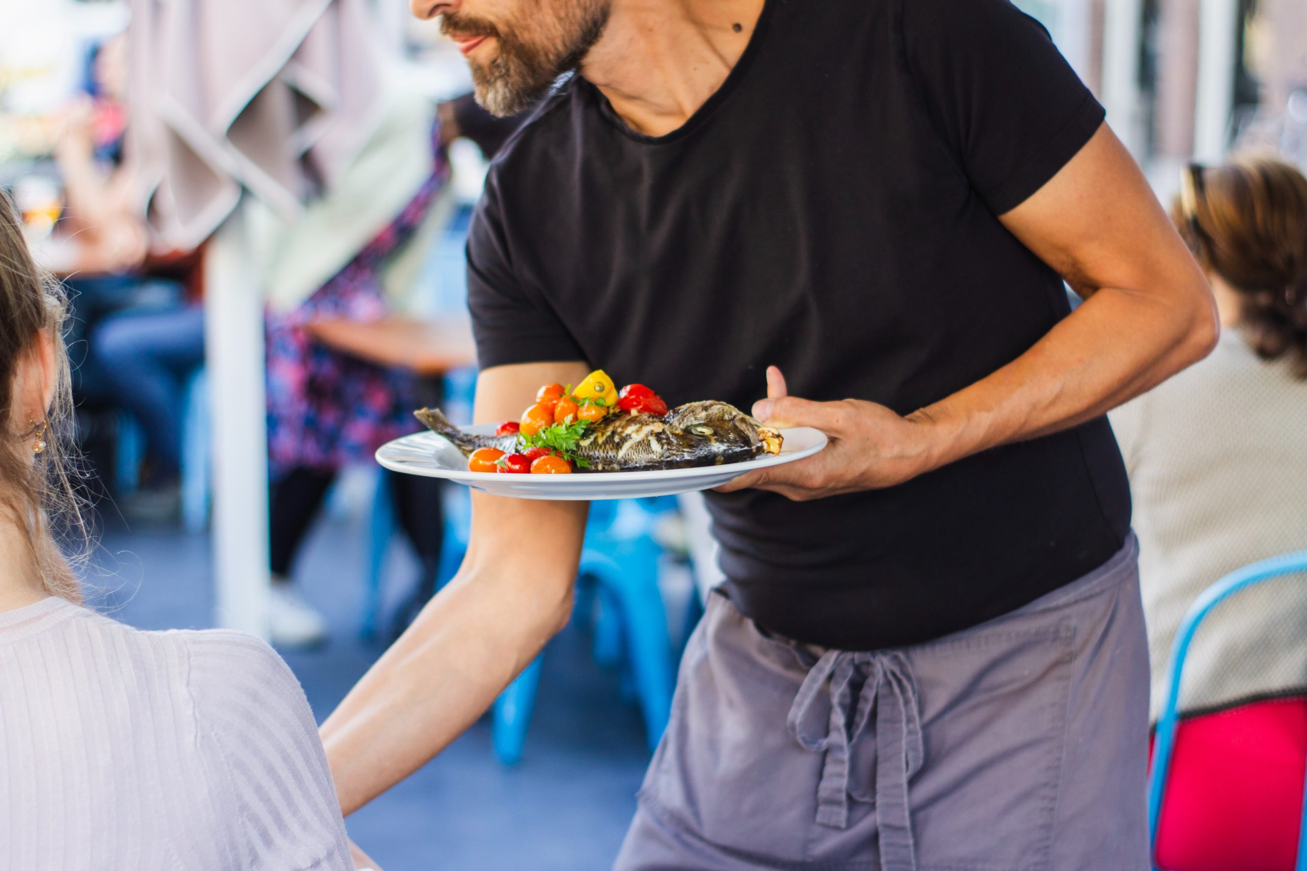 Waiter bringing a plate of fish to a table