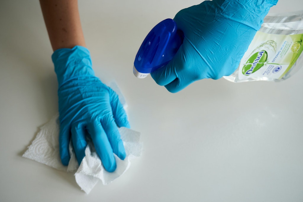 Spraying cleaner with two gloved hands